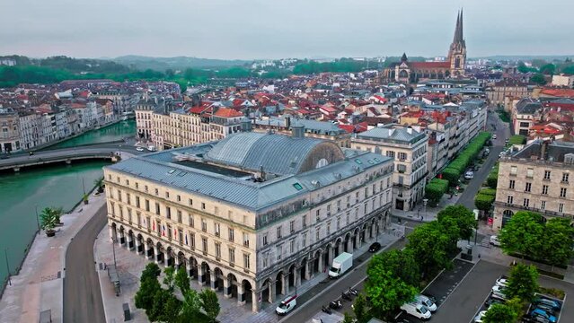 Aerial view of Bayonne city in Basque Country region by the river. Narrow medieval streets and red rooftop buildings. Twin towers rise from hilltop Gothic cathedral with medieval cloisters in France.