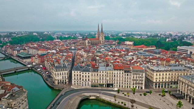 Aerial view of Bayonne city in Basque Country region by the river. Narrow medieval streets and red rooftop buildings. Twin towers rise from hilltop Gothic cathedral with medieval cloisters in France.