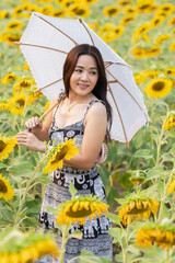 Beautiful Asian girl in sunflower field. Portrait happy young woman posting in sunflower field. Travel ,Summer and Vacation Concept
