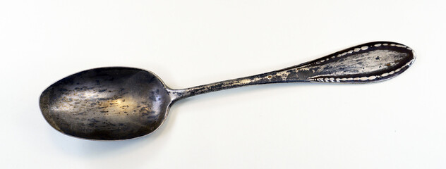 Retro antique silver spoon covered with black patina, isolated on white, close-up