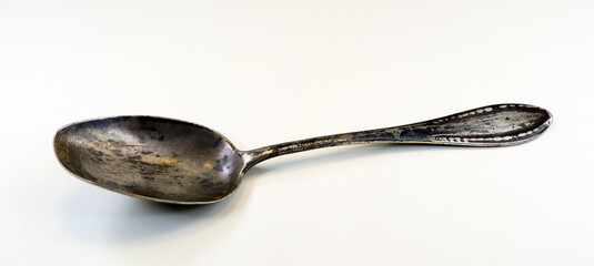 Retro antique silver spoon covered with black patina, isolated on white, close-up 