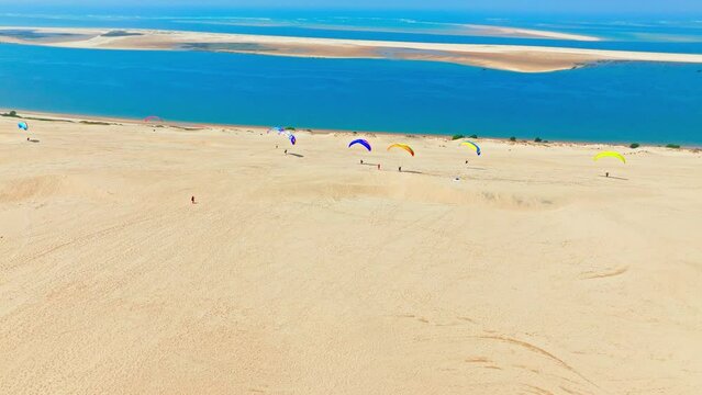 Panoramic view on the tallest sand dune in Europe, a Natural feature in France. Aerial view of tourists enjoying paragliding at the famous Dune of Pilat alongside the shore in France.