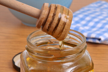 Miel liquide coulant d'une cuillère à miel en bois dans un pot de miel