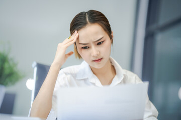 Asian people, In the corporate office, a young businesswoman sits at her desk, feeling exhausted...