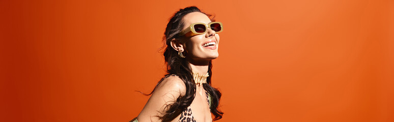 A stylish woman in a leopard print dress and sunglasses poses confidently in a studio against an...