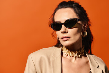 A stylish woman is seen wearing sunglasses and a tan jacket against an orange background, embodying summertime fashion.