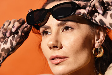 A stylish woman exudes summer vibes as she confidently wears sunglasses and a chic scarf on her...