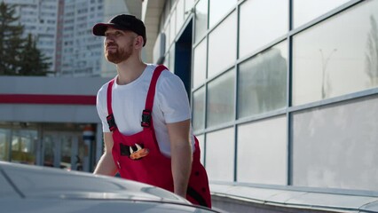 At automotive service center mechanic skillfully attends to car with its hood exposed, embodying role of repair master demonstrating importance of their work in ensuring reliable car repair services.