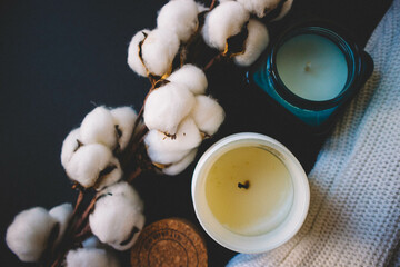 Candles, sweater and cotton on a black background. Copy space