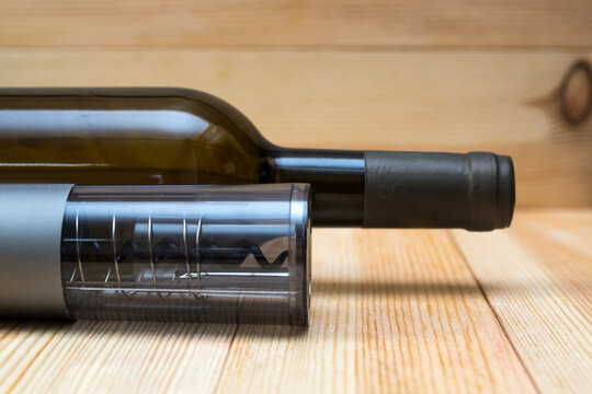 Electric corkscrew, wine bottle and film opener a light wood background.