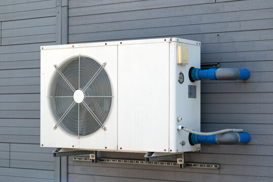 Condensing unit of air conditioning systems. Condensing unit installed on the gray wall.