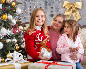 Mom with two daughters hugging in Christmas interior
