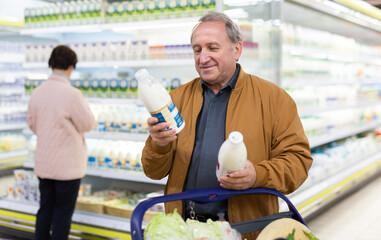 Elderly man chooses milk in supermarket