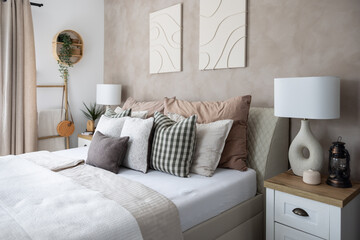 Modern bedroom interior, white blanket, lots of pillows and stylish night lamps