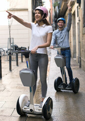 Young couple guy and girl walking on segway in streets of european city