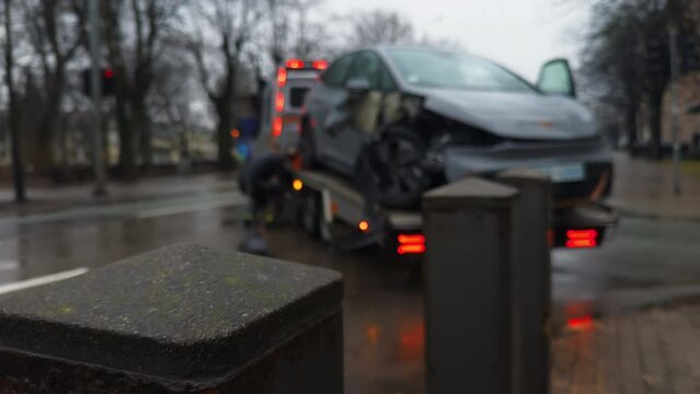 Tow truck transporting a damaged car in city street