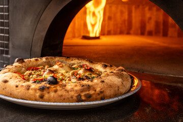 A savory Neapolitan pizza emerges from a blazing wood-fired restaurant oven, embodying the essence...