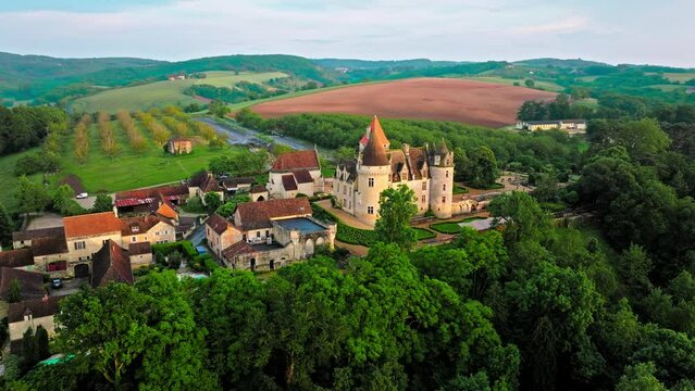 Cinematic stained glass castle with mullioned windows and rooms opening into the valley in France. Aerial view of Château des Milandes fortress at golden sunset in France,