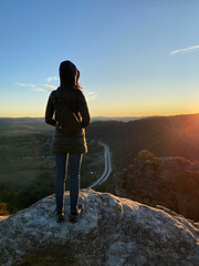 Person on the top of a mountain. Silhouette of a woman looking at the sunset over the blue...