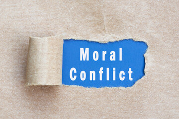 Moral conflict text on brown paper with torn hole. - obrazy, fototapety, plakaty