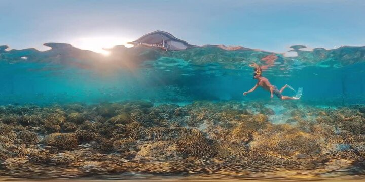 360 vr footage of the freediver swimming underwater in the tropical sea and swimming near the traditional building in West Papua region in Indonesia