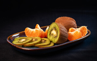 Fresh kiwi and tangerine fruits on a plate