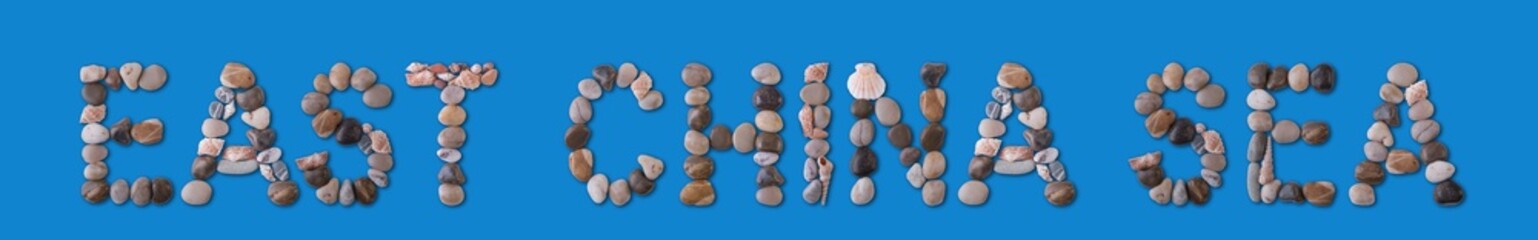 The geographical inscription “East China Sea” is lined with shells and stones of various shapes on a harmonious blue background. Water tourism, marine geology, study and ecology of the World Ocean