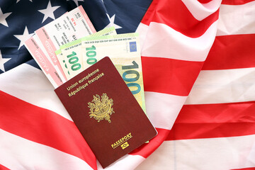 French passport and euro money with airline tickets on United States national flag background close up. Tourism and diplomacy concept