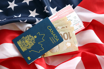 Canadian passport and money on United States national flag background close up. Tourism and diplomacy concept