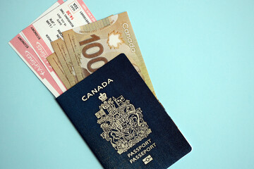 Naklejka premium Canadian passport with money and airline tickets on blue background close up. Tourism and travel concept