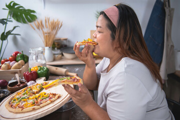 Fat Asian woman sitting and eating pizza that she made herself. The taste is very delicious. Food and health concept