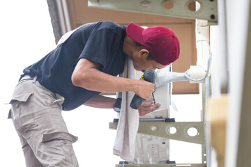 Male technician hands using a screwdriver fixing modern air conditioner, repairing and servicing,...