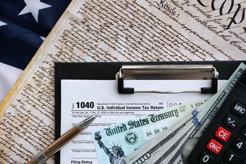 United States 1040 tax form individual income tax return with refund check and US dollar bills...