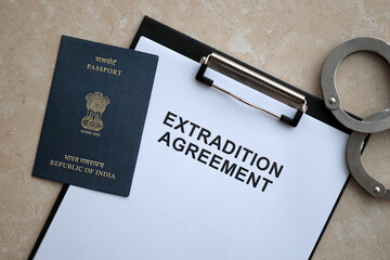 Passport of India and Extradition Agreement with handcuffs on table close up