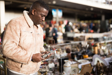 Man looking at used items at a flea market - obrazy, fototapety, plakaty
