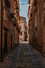 Fototapeta na wymiar Centro storico di Tropea in Calabria. Piccola strada acciottolata ed edifici residenziali in pietra.