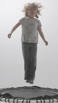 small girl jumping on a trampoline in vertical