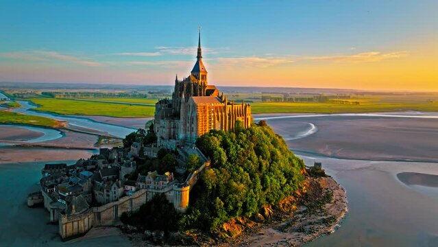 Aerial dramatic sunset over iconic French castle in Europe. Mont Saint-Michel on a tidal island in Normandy, France.