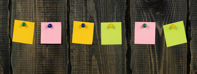 Blank notepaper and space for text with push pins on wooden background. note blank color paper...