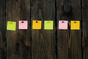 Blank notepaper and space for text with push pins on wooden background. note blank color paper...