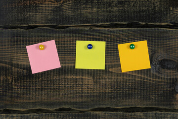Blank notepaper and space for text with push pins on wooden background. note blank color paper cards on wooden board. noticeboard. blanks for designers