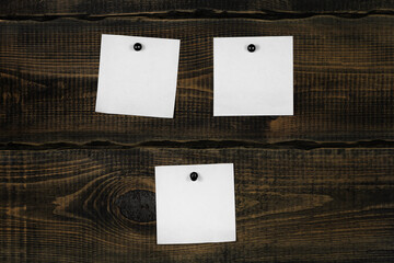White blank notepaper and space for text with push pins on wooden background. note blank color paper cards on wooden board. noticeboard. blanks for designers