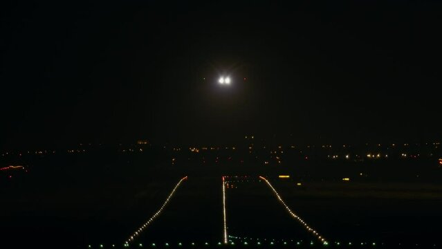 The airplane approaches the runway with the landing lights on in the dark and makes a landing