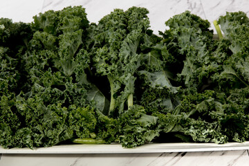 Close up of a tray of green fresh kale on a kitchen counter