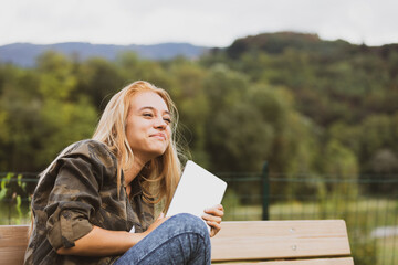 Tablet companion, young woman laughs in tranquil park