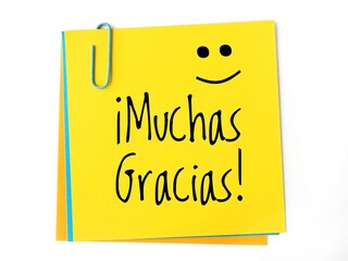 ¡Muchas gracias! handwritten on a yellow sticky note and a happy face. Thank you very much in spanish