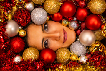 Young woman face surrounded by Christmas's balls.
