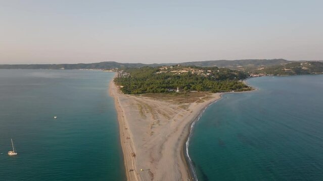 The drone flies backwards over the clear waters and sandy beach of Cape Possidi in Halkidiki, Greece