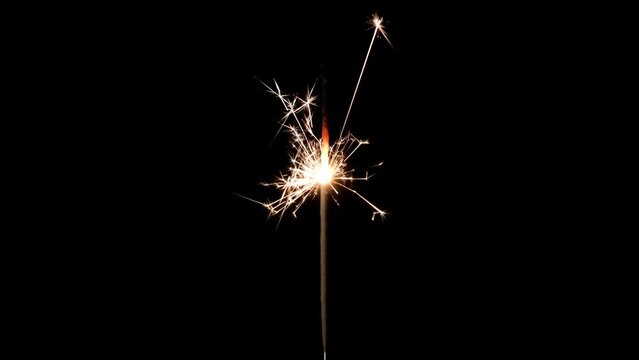 Christmas or Happy New Year concept. Close-up banner of Bright Burning Sparkler on a black background. 4k resolution video of burning sparkler and sparks.