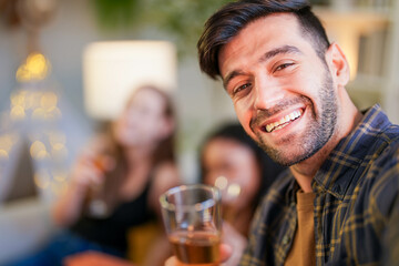Friends captured mid-laughter as they toast in a stylish home, taking a selfie to remember the cheerful occasion